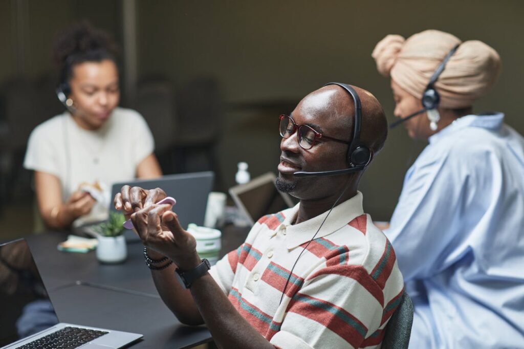 A group of diverse professionals working at a call center desk, engaged with laptops and headsets.